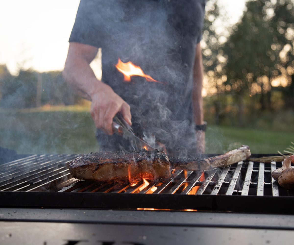 Man grilling Dismal River Beef with flames